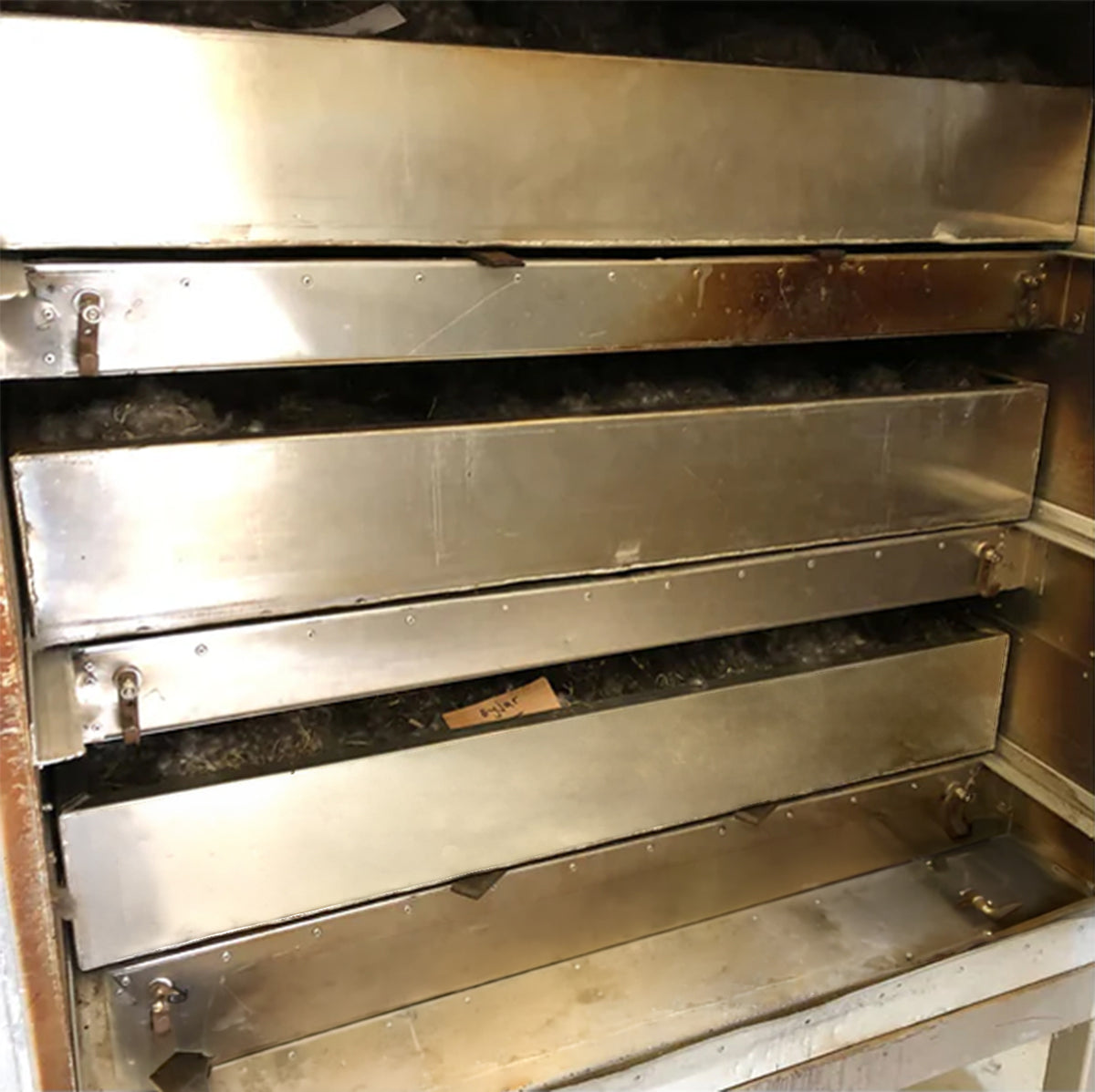 Große, gestapelte Metallschubladen einer Trocknungsanlage für die Verarbeitung von Eiderdaunen.