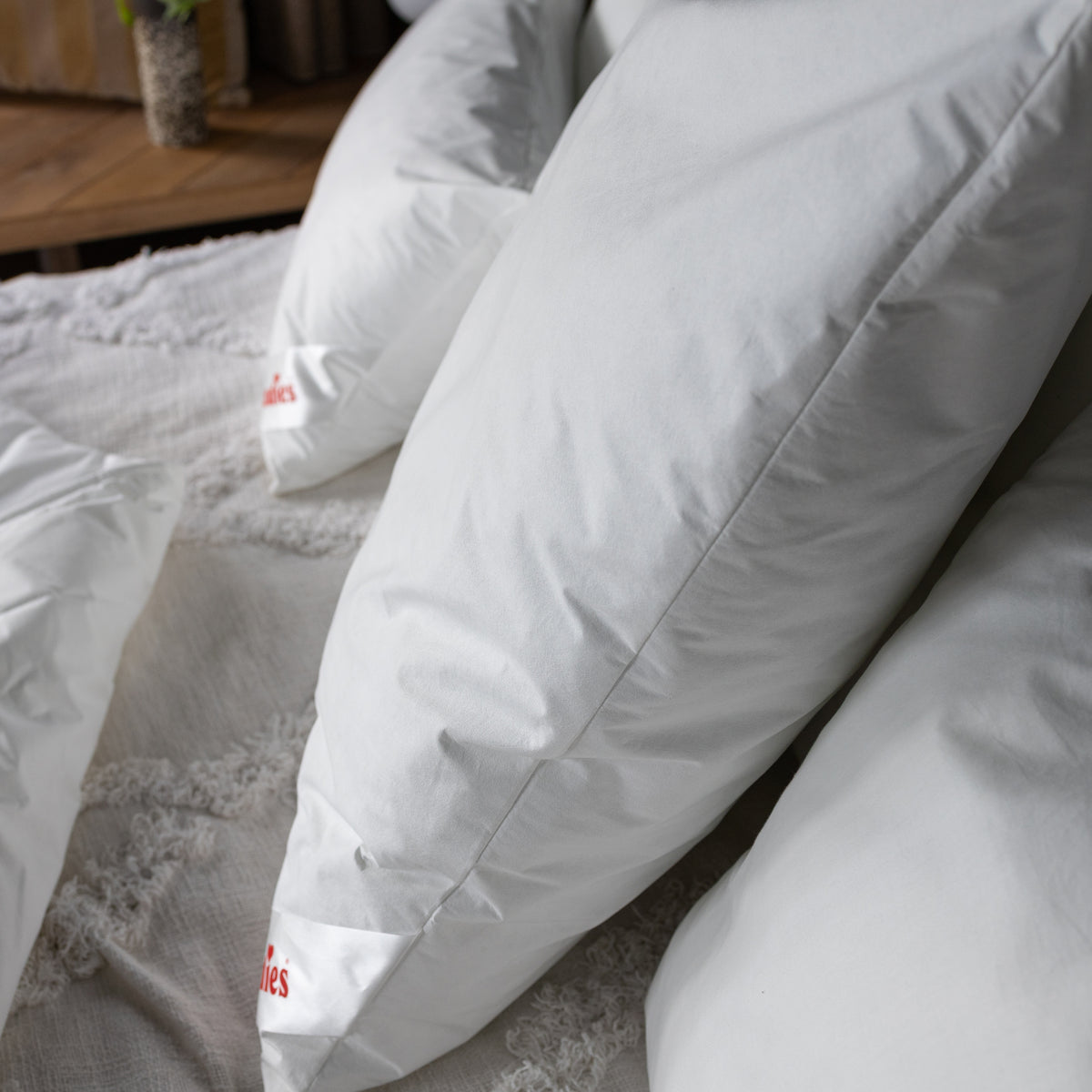 Seitenansicht von mehreren weißen Kissen auf einem Bett mit einer Decke im Hintergrund