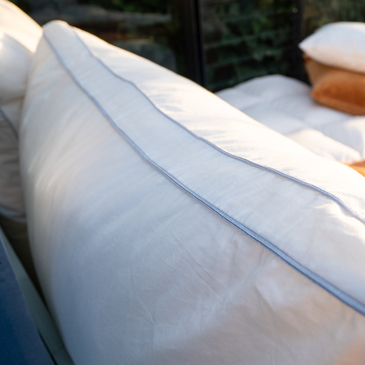 Nahaufnahme eines weißen Kissens mit Blauer Naht auf einem Bett