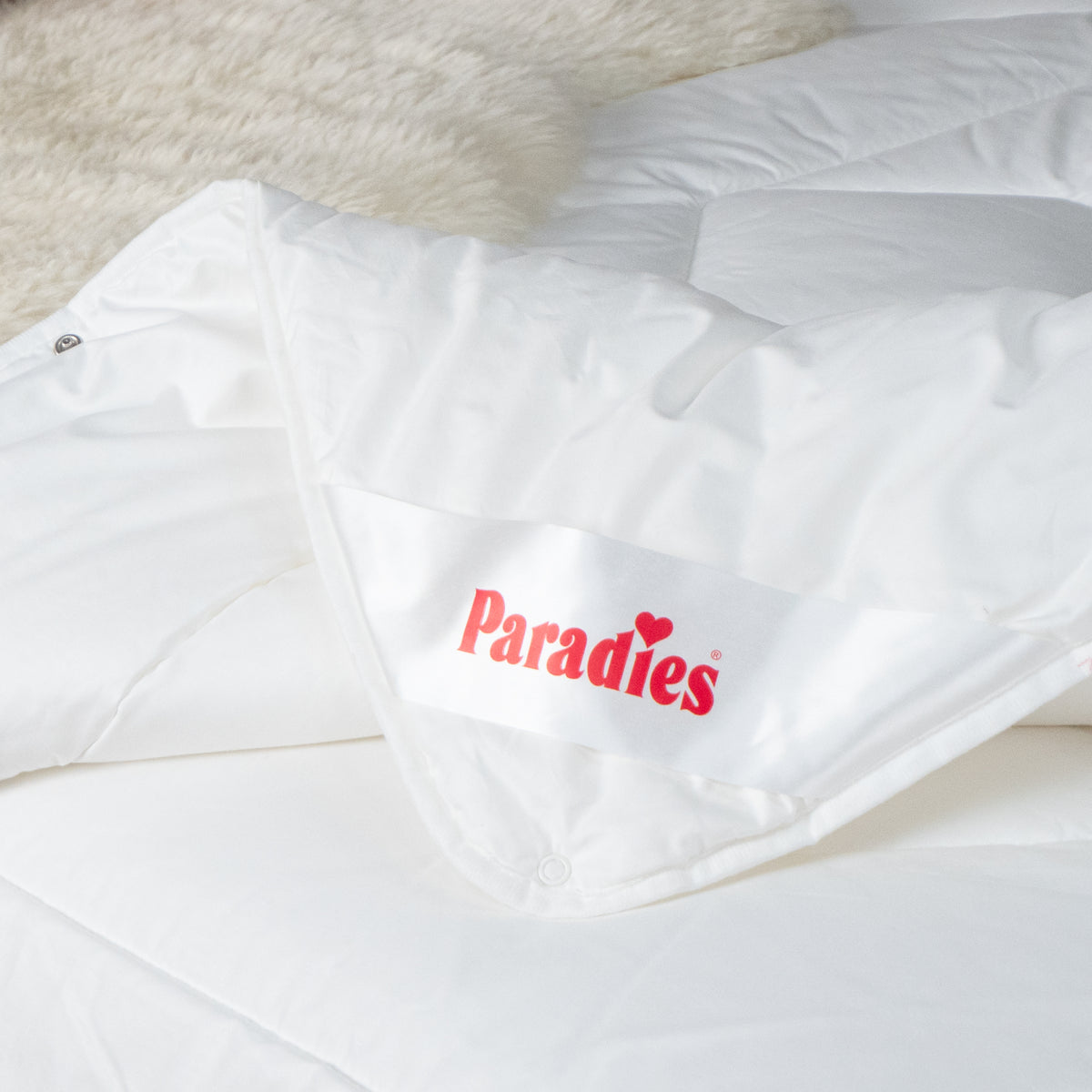 Weiße Bettdecke mit rotem Paradies-Logo auf einer weißen Matratze